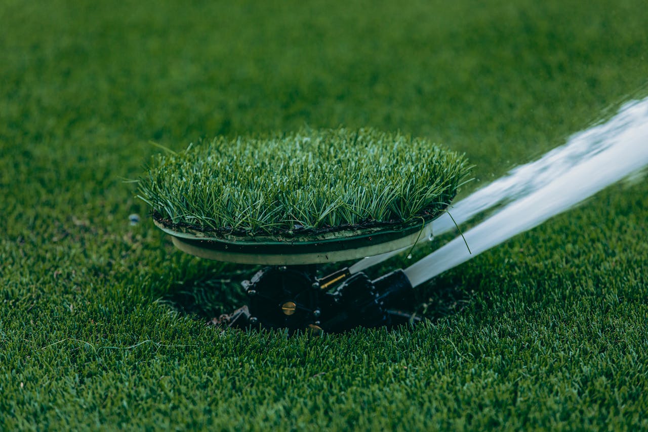 Close-up of an automatic sprinkler watering a lush green lawn, showcasing irrigation system.