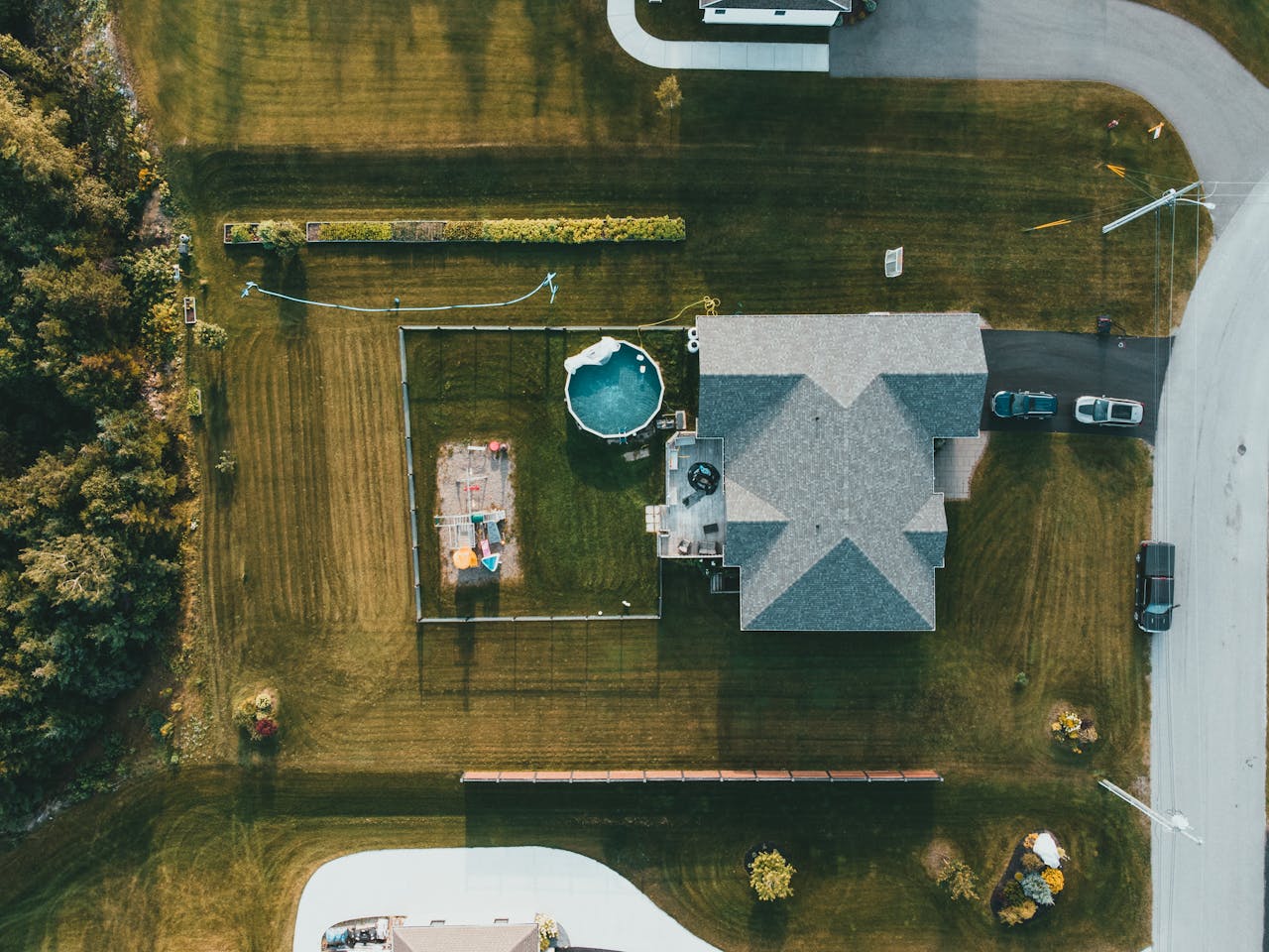 Drone shot of a house and garden with a swimming pool and play area.